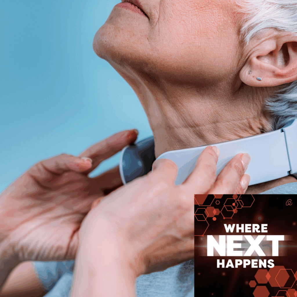 Close-up of an older woman’s neck as a clinician positions a handheld medical scanning device against her throat, with text overlay reading “WHERE NEXT HAPPENS.”